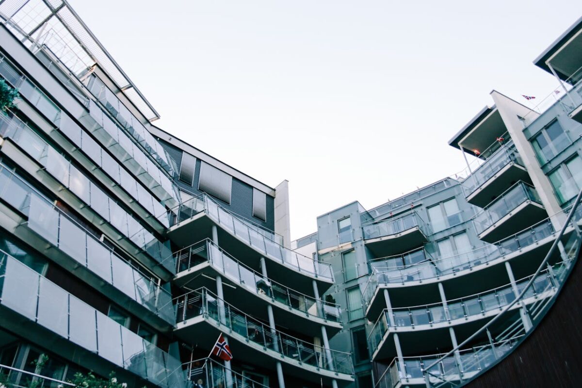 From below of contemporary unusual building with glass walls with Norway flag hanging on balcony