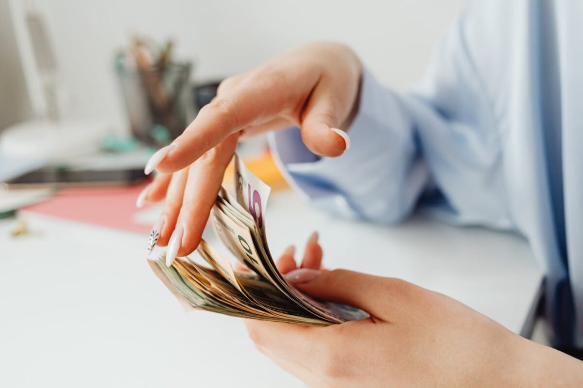 Close-up of a woman's hand counting euro banknotes on the office desk.